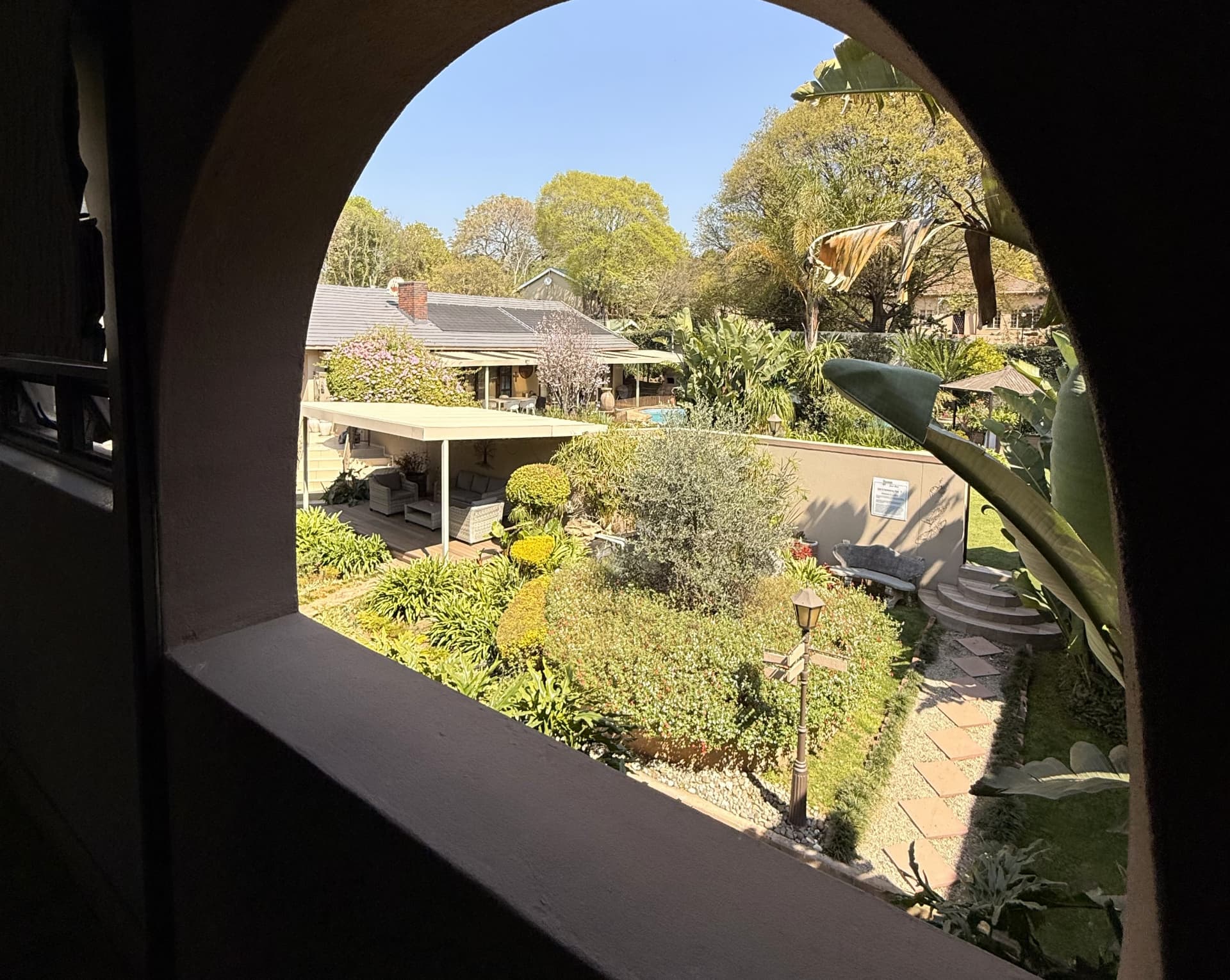 View through an arched opening at Dunton onto the garden lounge deck, fountain and paths