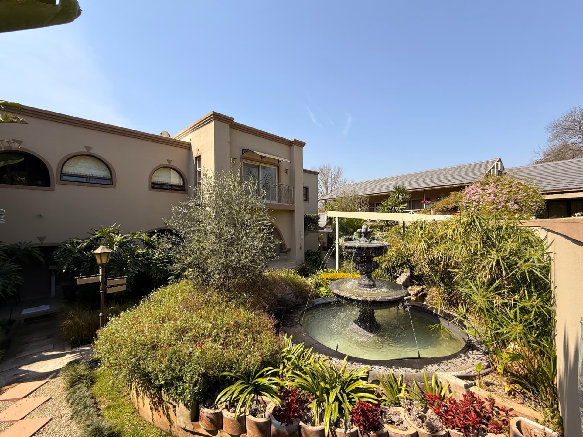 Fountain, garden beds and the guest house facade at Dunton Guest House