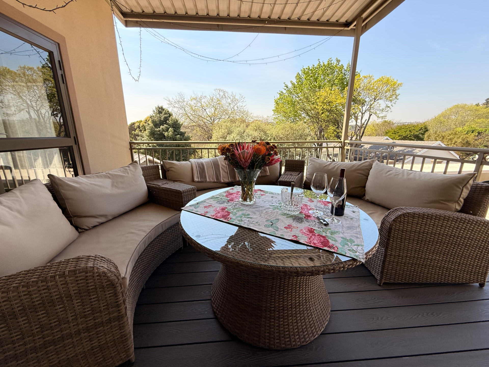 Close view of the covered patio's wicker seating, flowers, table settings and treetop view