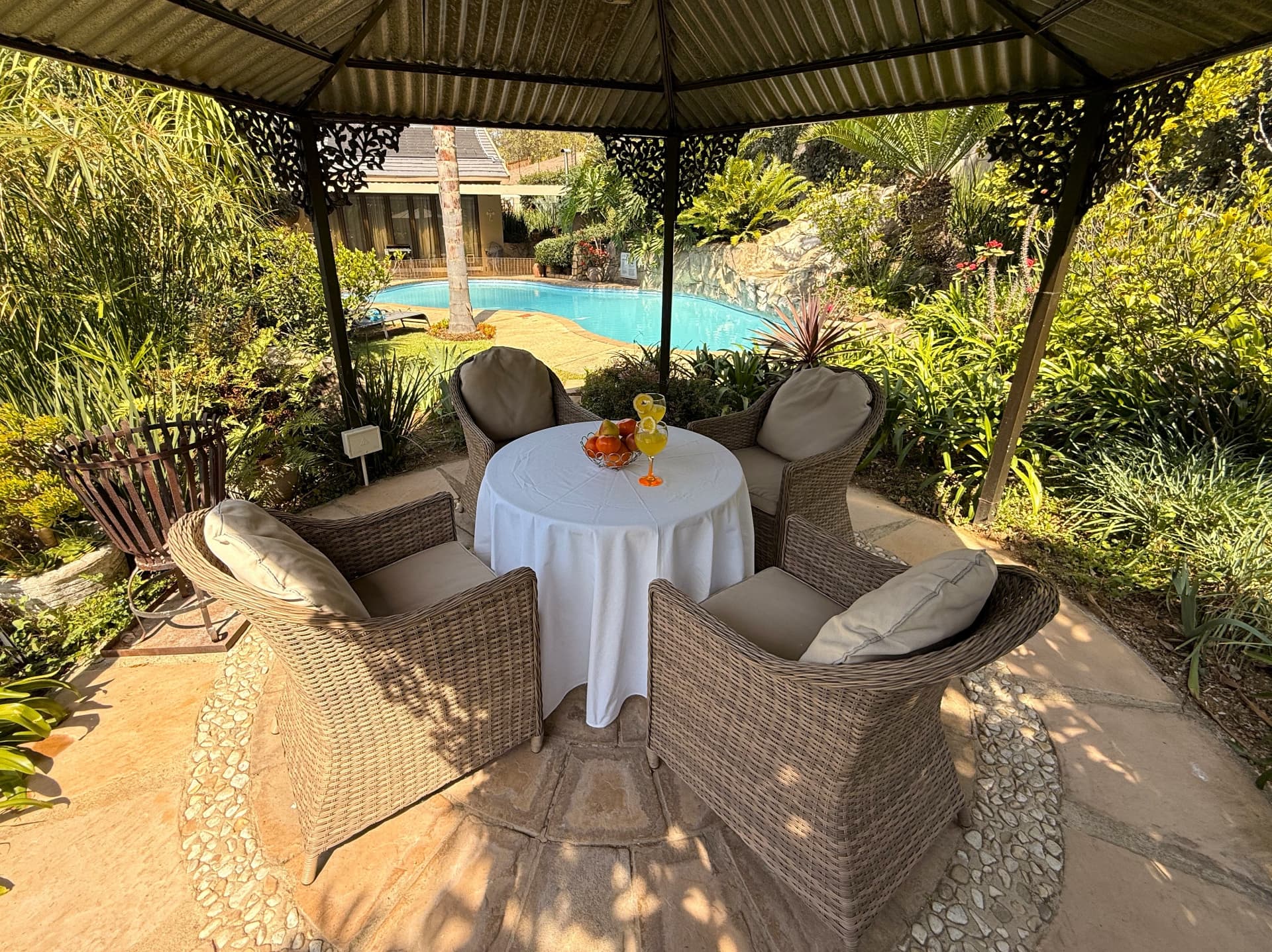 The garden gazebo at Dunton set with a table, juice and fruit, looking onto the pool