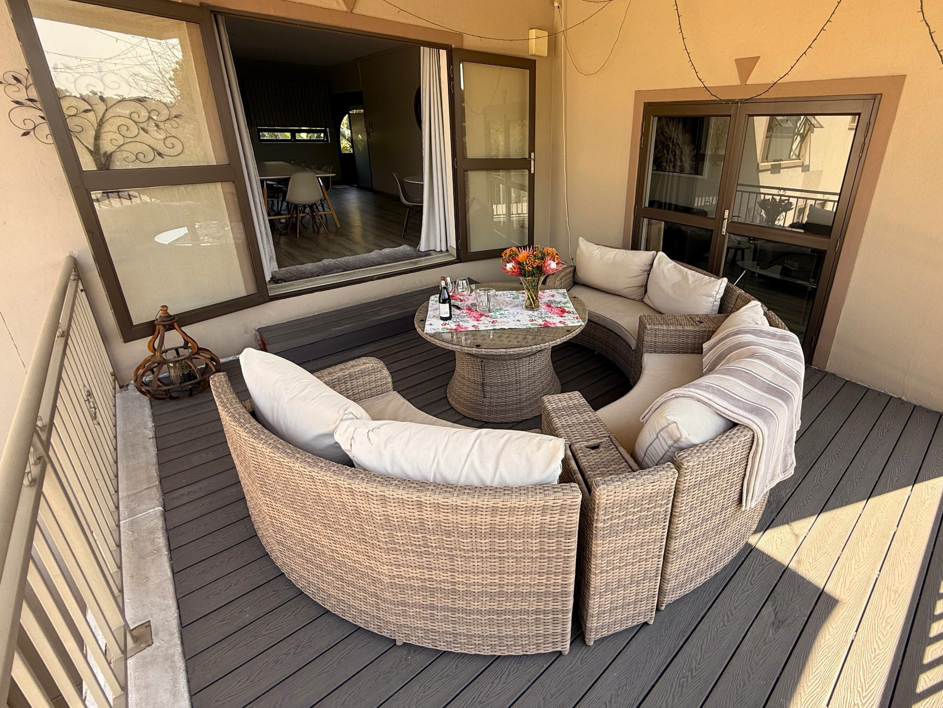 Sunlit private patio adjoining the meeting room with wicker seating, cushions, a round table and dark decking